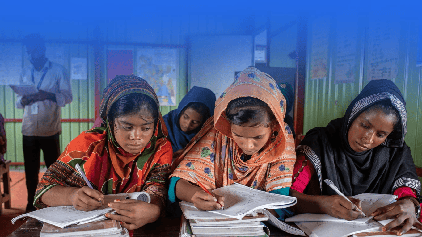 Young girls studying in a classroom with books and notebooks while learning in a supportive and safe environment