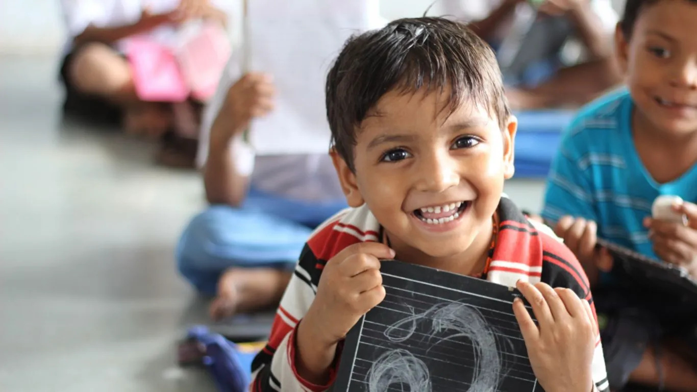 Smiling schoolchildren carrying backpacks and books as they return to school in a developing community