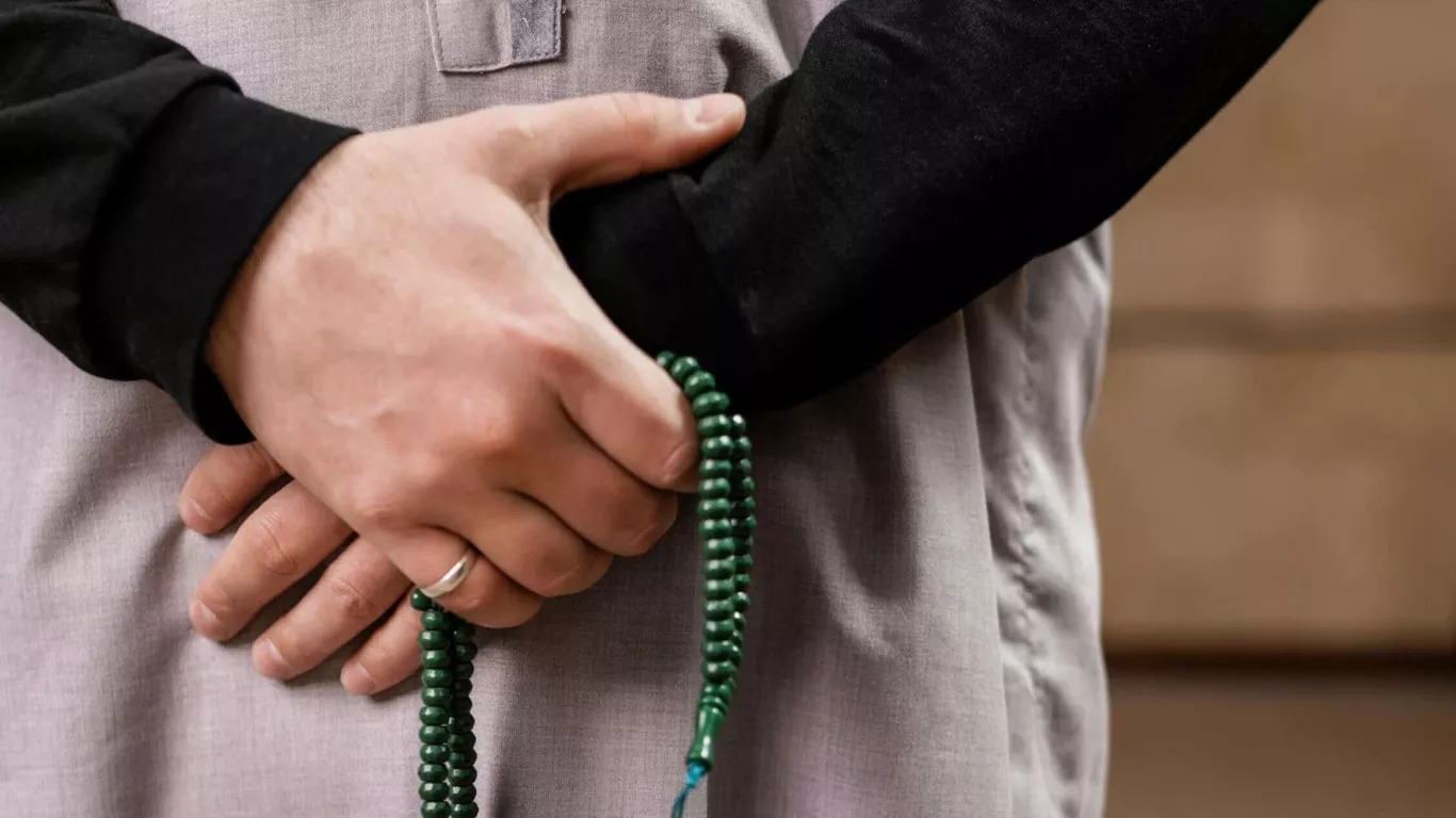 Muslim person holding prayer beads and making dua while giving charity digitally during the first ten days of Dhul Hijjah