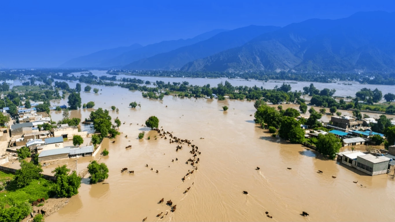 Flood affected families in northern Pakistan standing near damaged homes after heavy monsoon rains in 2025